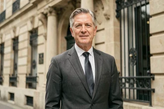 Portrait d'un homme élégant en costume gris devant un bâtiment institutionnel français à l'architecture classique